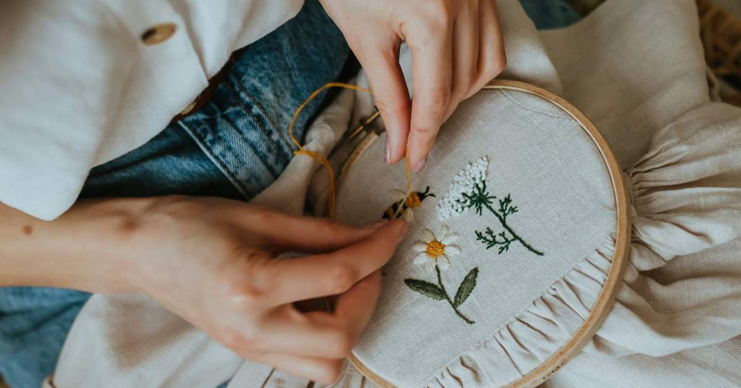 a woman is stitching a flower on a pillow 4x3 1